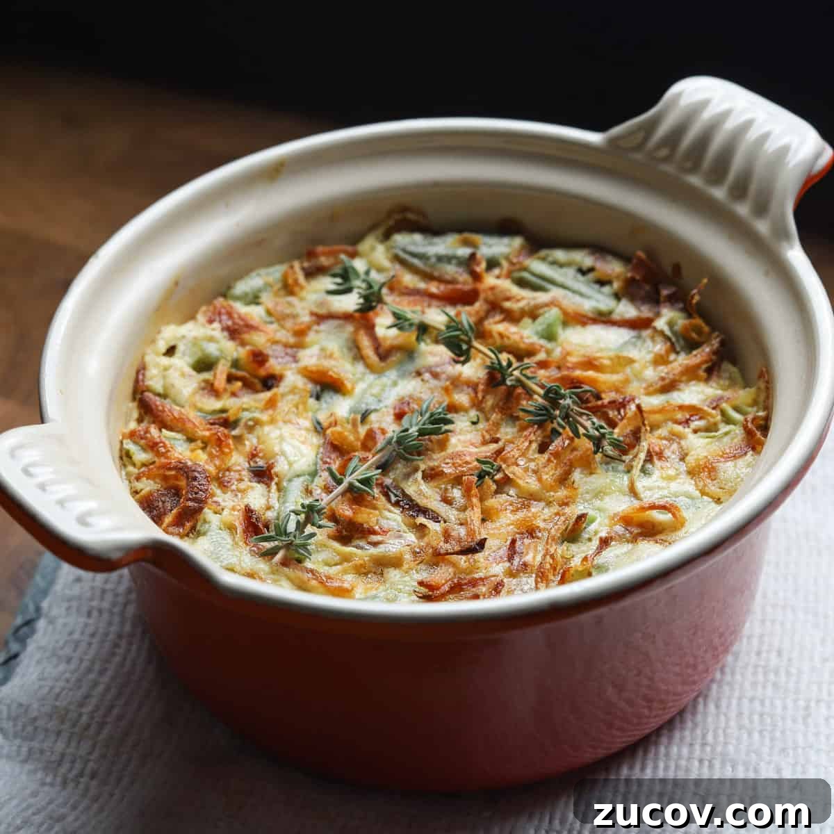 Vegan Green Bean Casserole Recipe with Crispy Onion Topping 3 Photo of an individual portion of vegan green bean casserole in a small le crest dish.