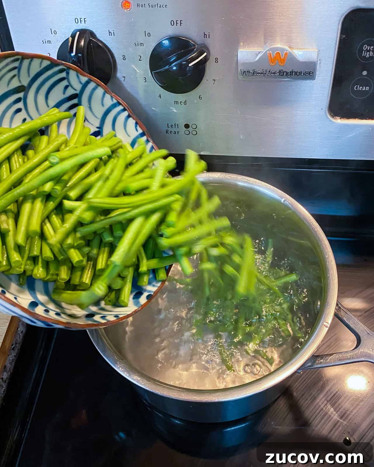 Vegan Green Bean Casserole Recipe with Crispy Onion Topping 5 Photo of fresh green beans being poured into a pan of boiling water.