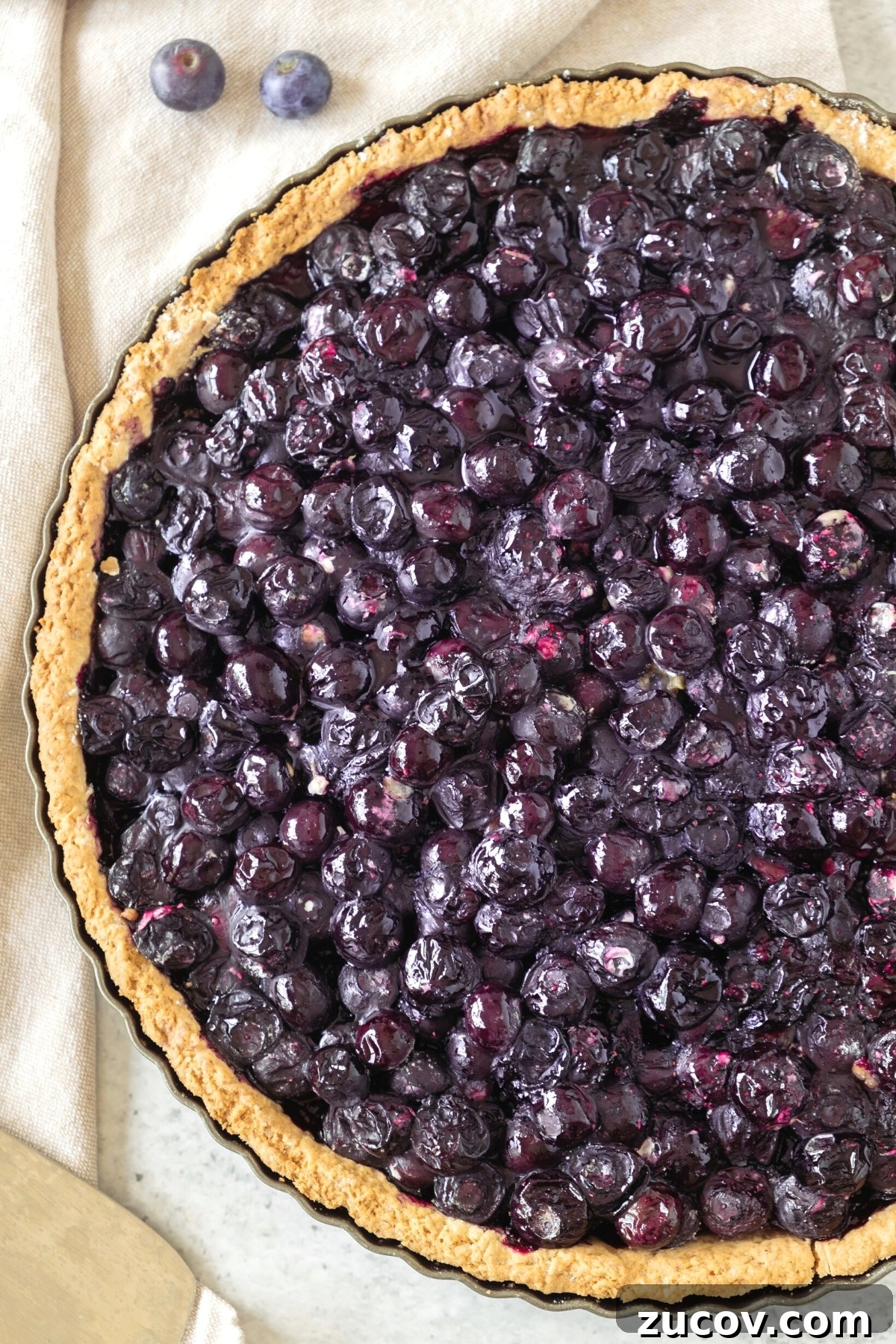 Gluten-Free Blueberry Pie (Dairy-Free) Up close shot of freshly baked blueberry pie on kitchen towel.