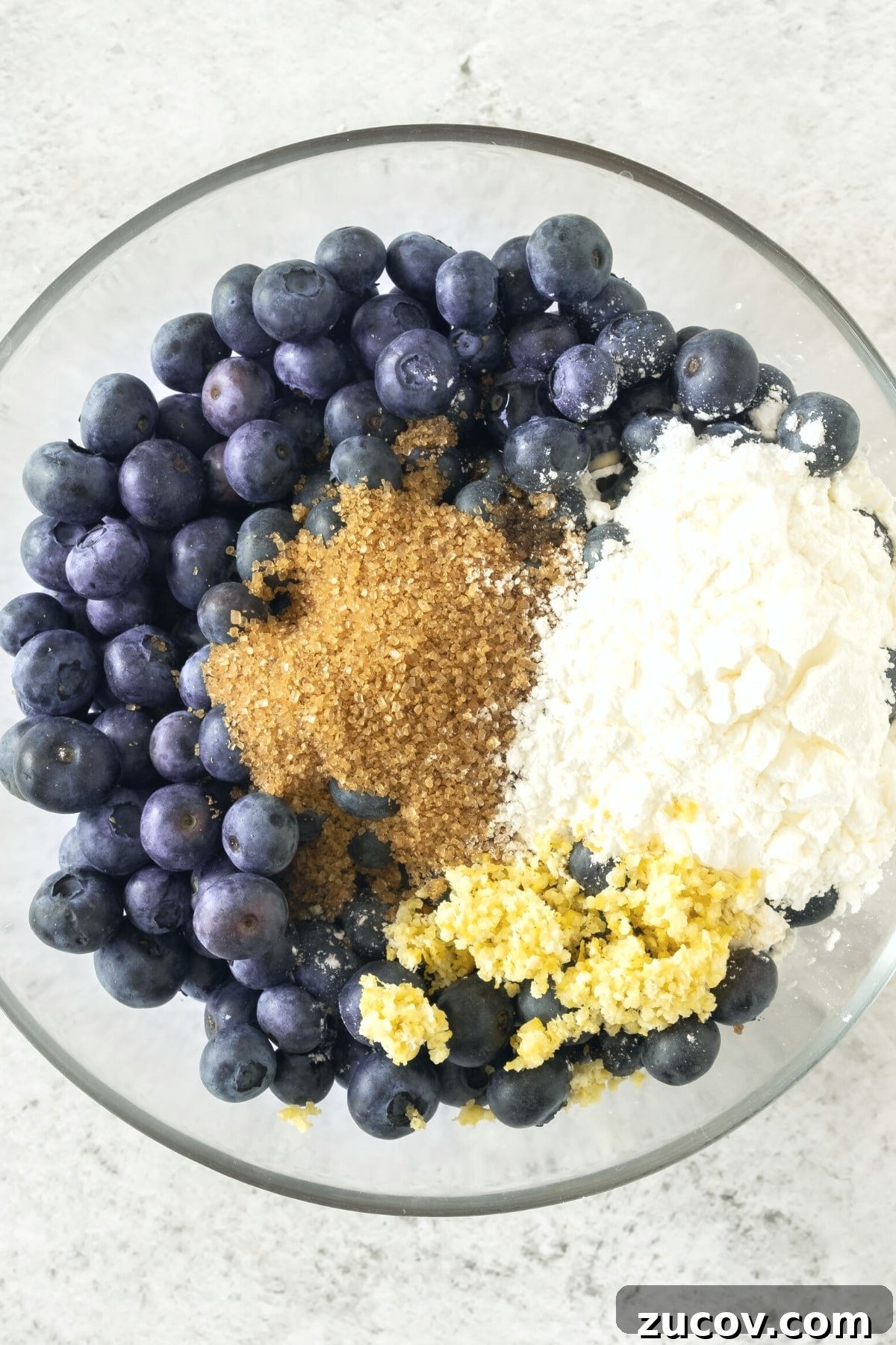Gluten-Free Blueberry Pie Filling (Dairy-Free) Fresh blueberries, brown sugar, lemon zest and corn starch in a glass bowl.