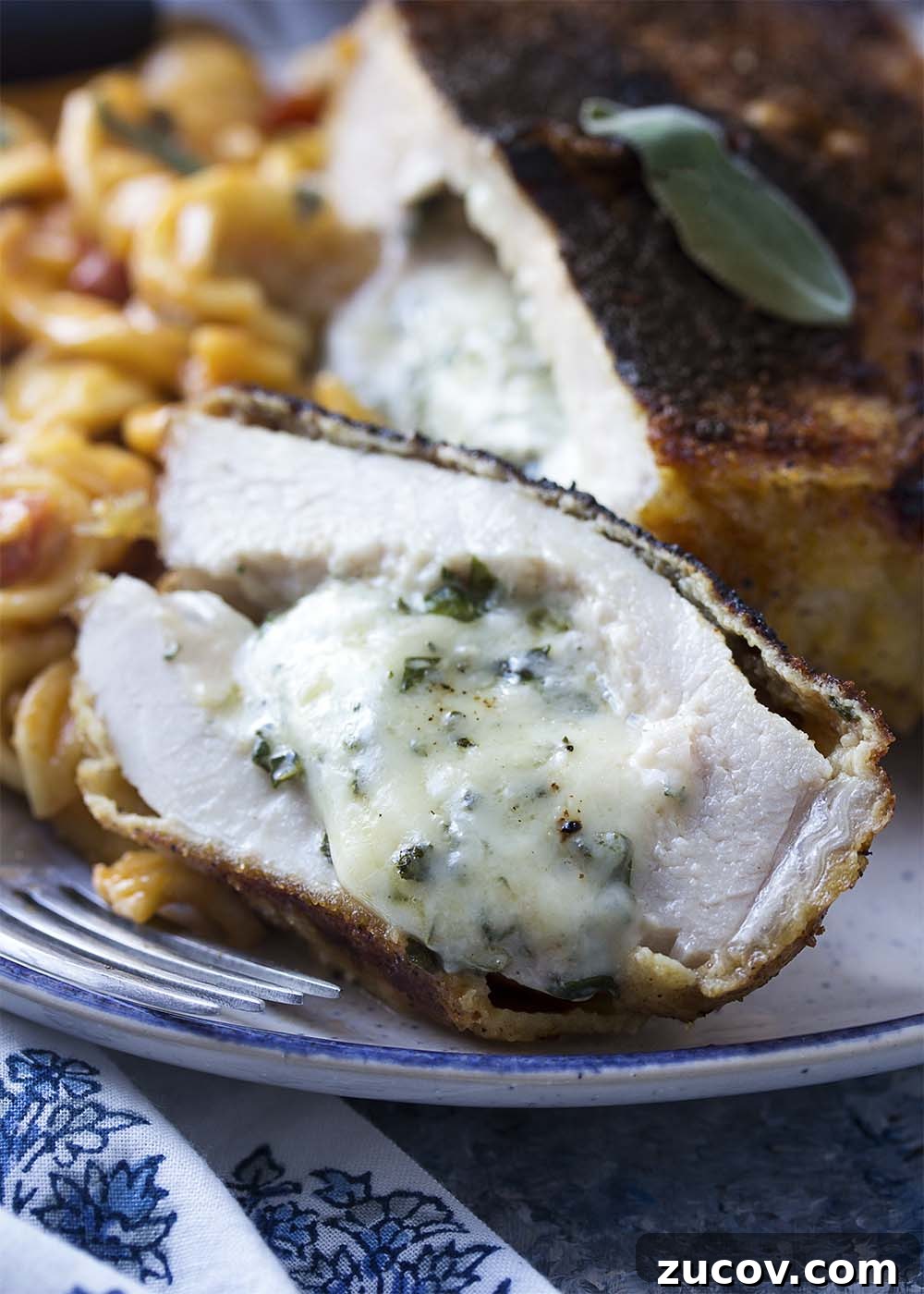 Cheese oozing from stuffed pork chop. Close up of a slice of pork to show the melted cheese and herbs oozing out.