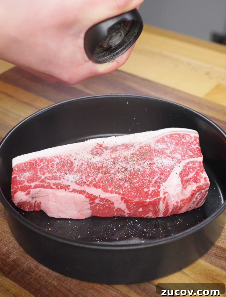 Crying Tiger Steak Recipe: Grilled Thai Marinated Flank Steak 4 Raw sirloin steak being seasoned generously with salt and black pepper before cooking for Crying Tiger Steak.