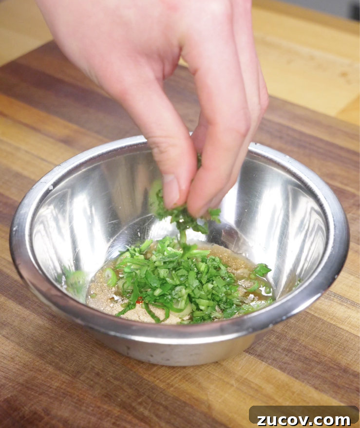 Crying Tiger Steak Recipe: Grilled Thai Marinated Flank Steak 5 Finely chopped cilantro being added to a bowl of Crying Tiger Steak sauce to build a fresh, herbal flavor.