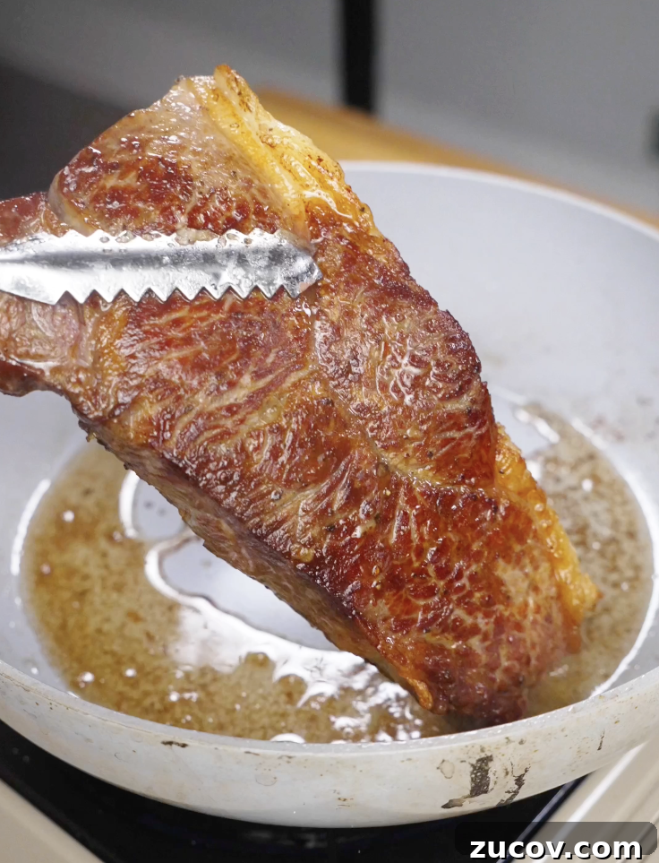 Crying Tiger Steak Recipe: Grilled Thai Marinated Flank Steak 6 Steak being seared in a hot pan with oil, developing a deep golden crust as the first step in making Crying Tiger Steak.
