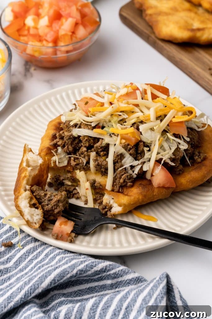 Navajo Tacos: Authentic Indian Fry Bread Recipe & Tips 13 loaded navajo fry bread taco on a white plate next to a black fork