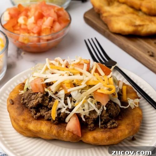 Navajo Tacos: Authentic Indian Fry Bread Recipe & Tips 14 loaded navajo fry bread taco on a white plate next to a black fork