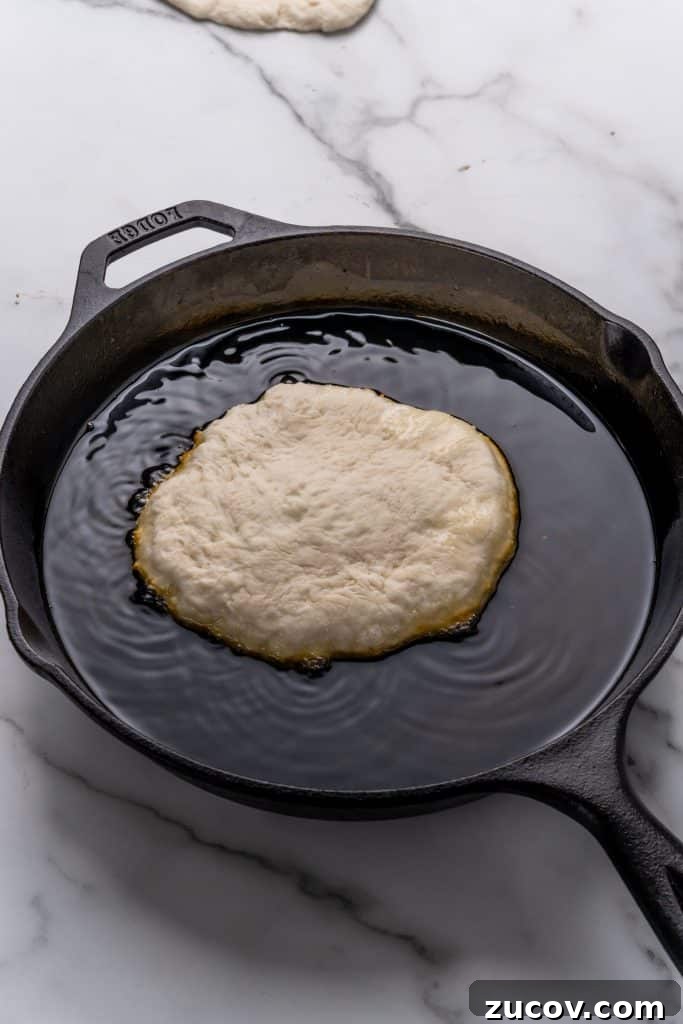 Navajo Tacos: Authentic Indian Fry Bread Recipe & Tips 10 a piece of Indian fry bread in a cast iron skillet filled with hot oil