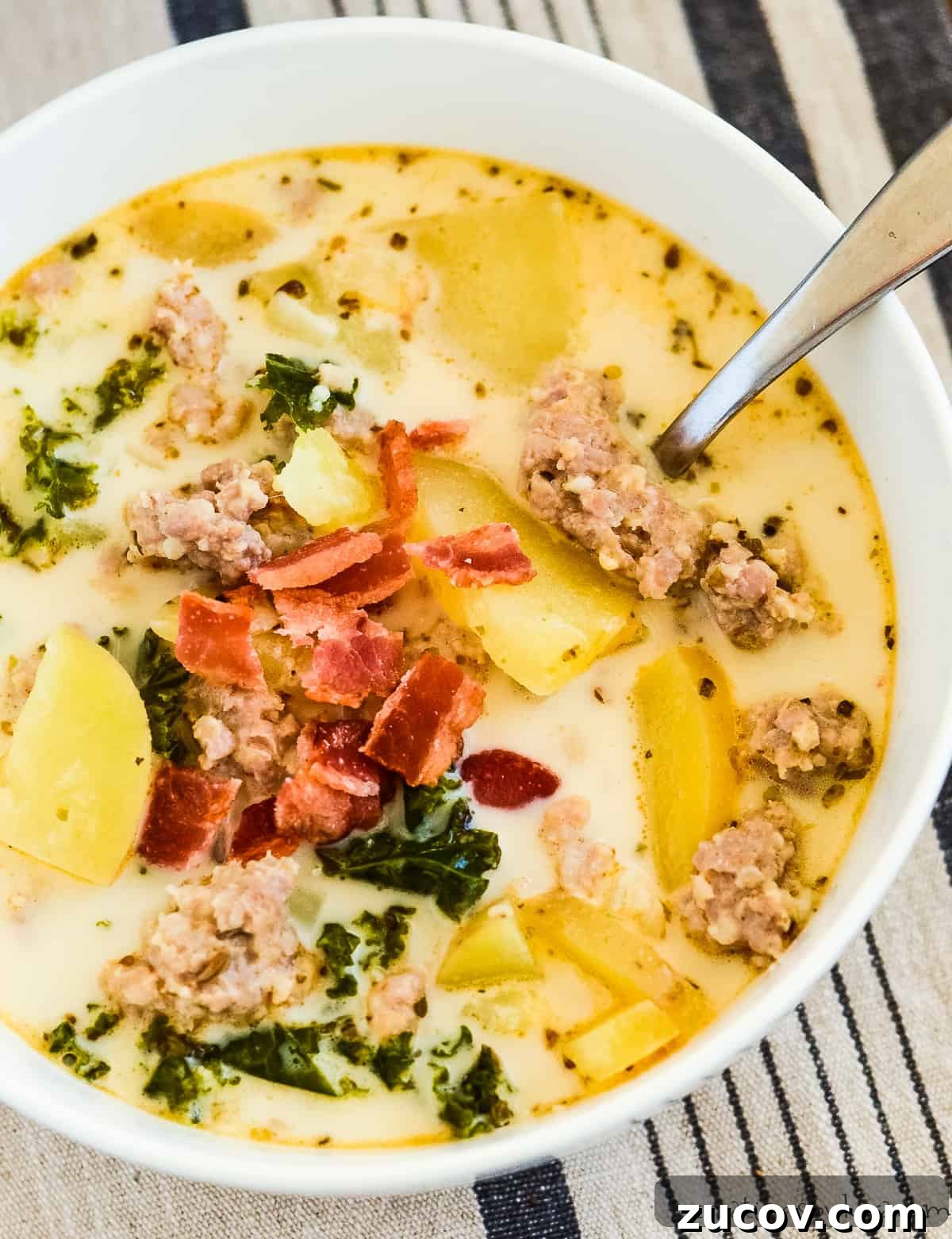 One-Pot Zuppa Toscana Recipe: Authentic Italian Sausage Soup 4 bowl of soup with a spoon in it