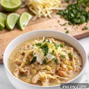 Slow-Cooker Creamy White Chicken Chili Recipe 14 A bowl full of a chicken chili topped with white cheddar cheese.
