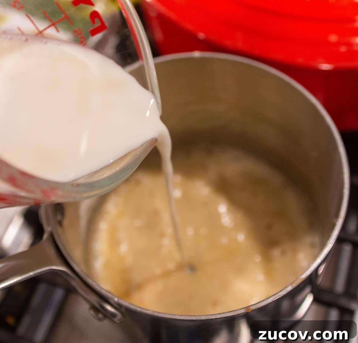 Slow-Cooker Creamy White Chicken Chili Recipe 9 Milk slowly being poured into a flour and butter mix to make a roux.
