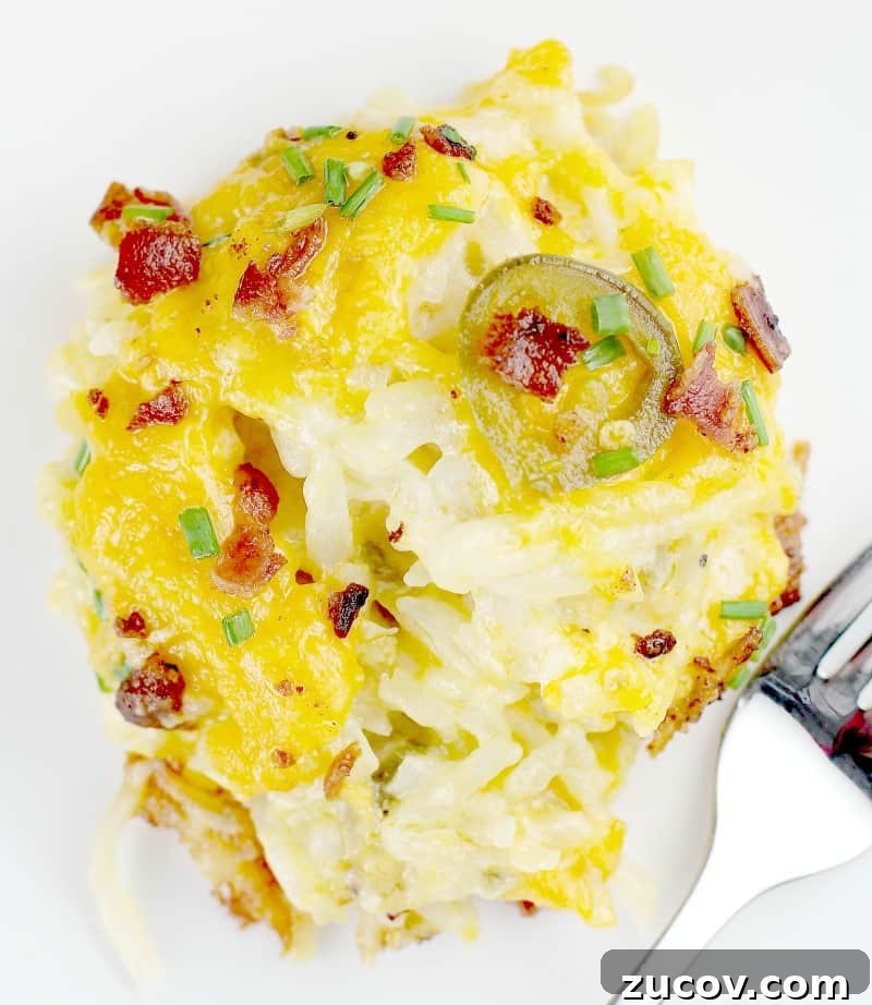 Jalapeño Popper Hash Brown Casserole Recipe for Spicy Comfort 5 close shot of a spoonful of potato casserole on a white plate