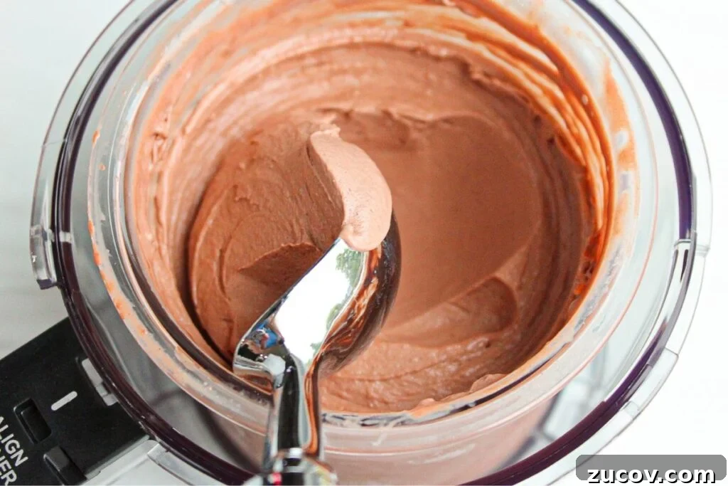 Creamy Cottage Cheese Ice Cream Recipe for Ninja Creami 6 A close up shot of chocolate cottage cheese ice cream in the ninja creami machine with a scoop of ice cream being scooped out.