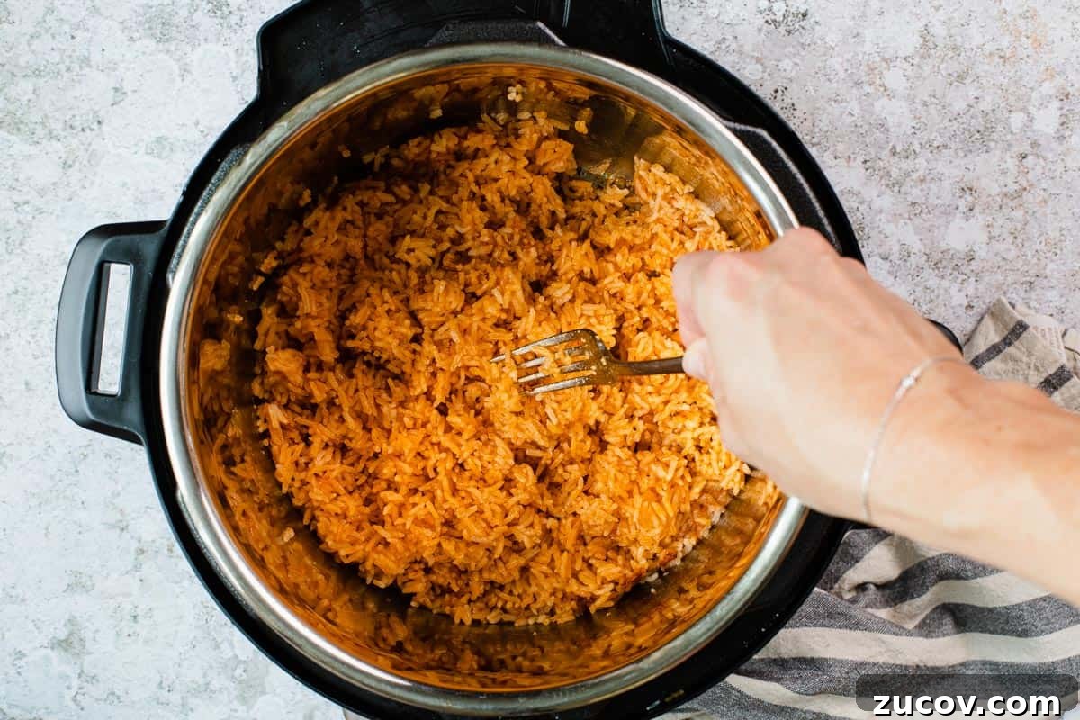 Instant Pot Arroz Rojo (Mexican Red Rice) 10 fluffing rice in an instant pot with a fork