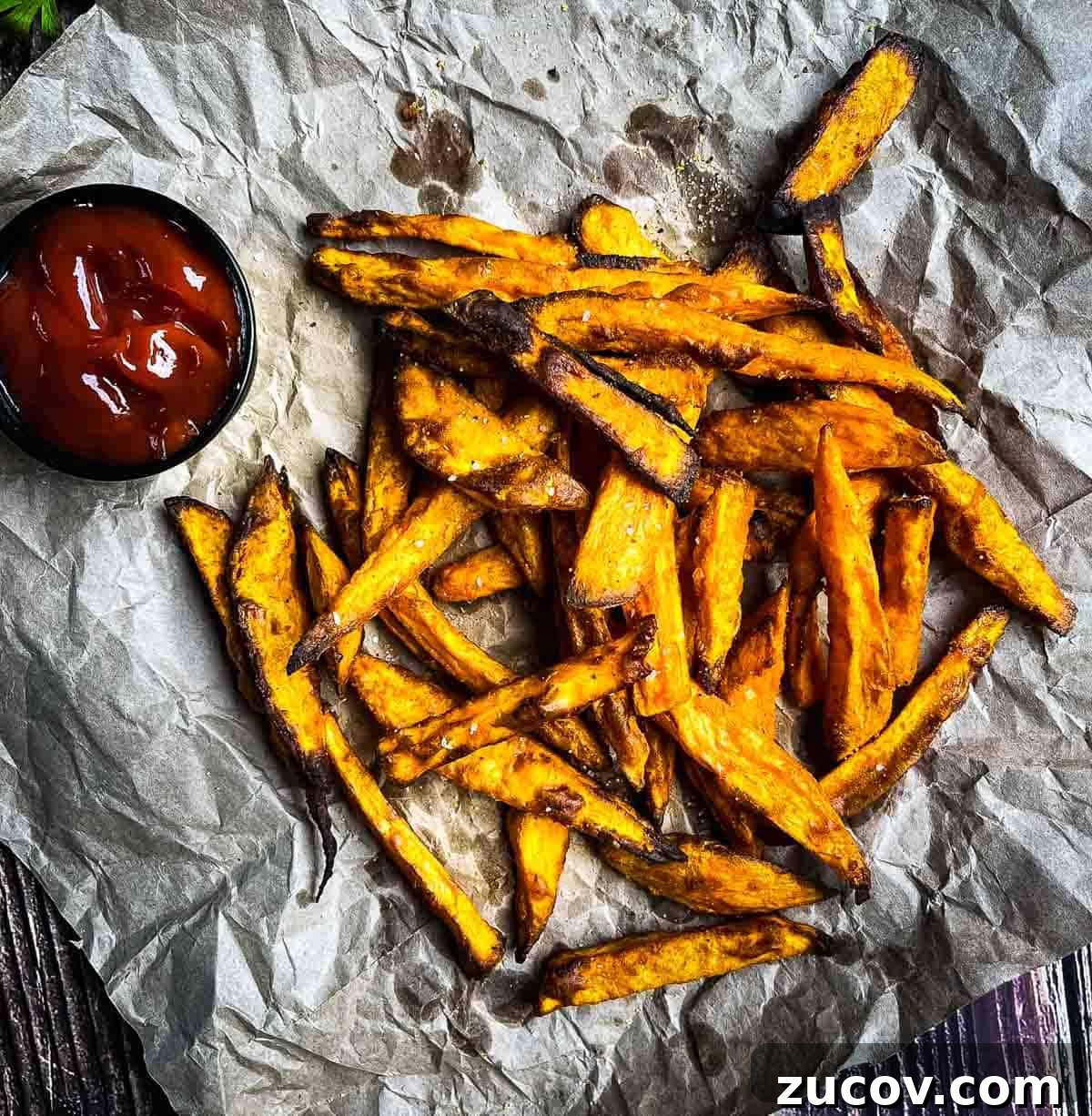 Crispy Air-Fryer Sweet Potato Fries Coated in Cornstarch 14 Ultra crispy air fryer sweet potato fries on brown paper with a side of ketchup.