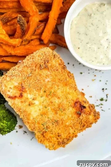 A halibut fillet on a white plate with homemade tartar sauce, sweet potato fries, and broccoli.