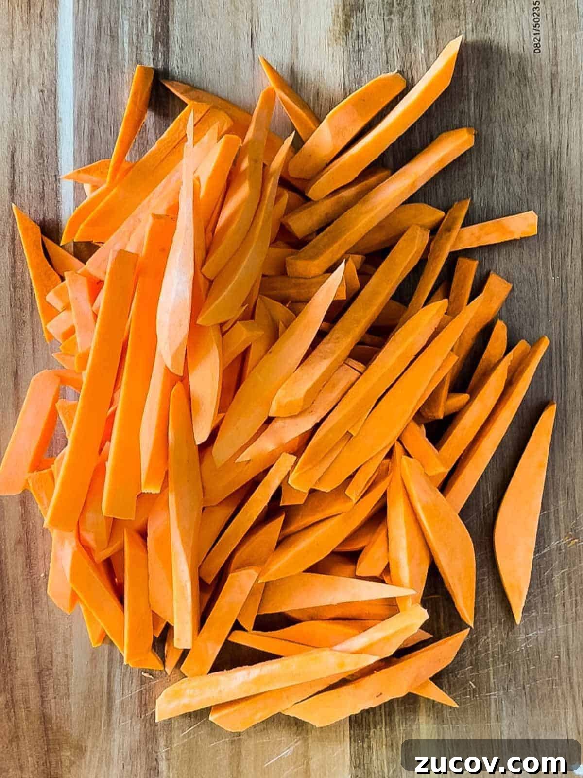 Crispy Air-Fryer Sweet Potato Fries Coated in Cornstarch 6 The sweet potatoes cut into fries and placed on a wooden cutting board.