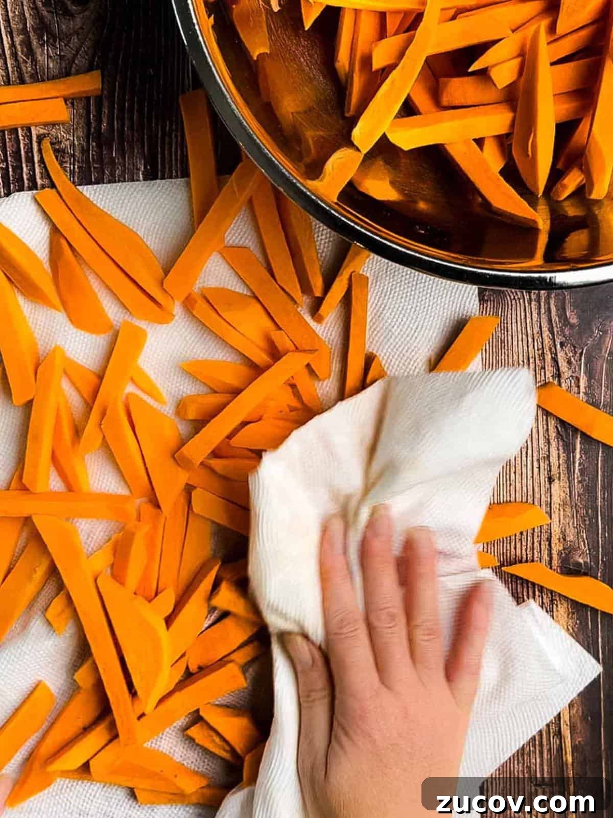 Crispy Air-Fryer Sweet Potato Fries Coated in Cornstarch 8 A hand using a paper towel to dry the sweet potato fries.
