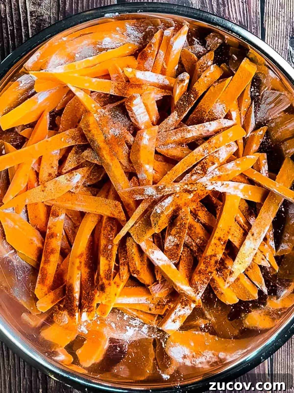 Crispy Air-Fryer Sweet Potato Fries Coated in Cornstarch 9 The fries in a large bowl with cornstarch and seasoning on them.