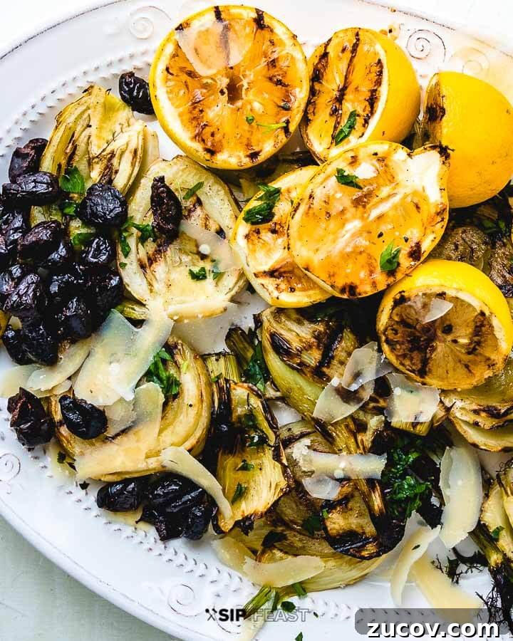 Grilled Fennel Salad - sipandfeast.com #grilledfennel #fennel #italiansalad #salad Fennel, lemons and black olives on white plate on green background.