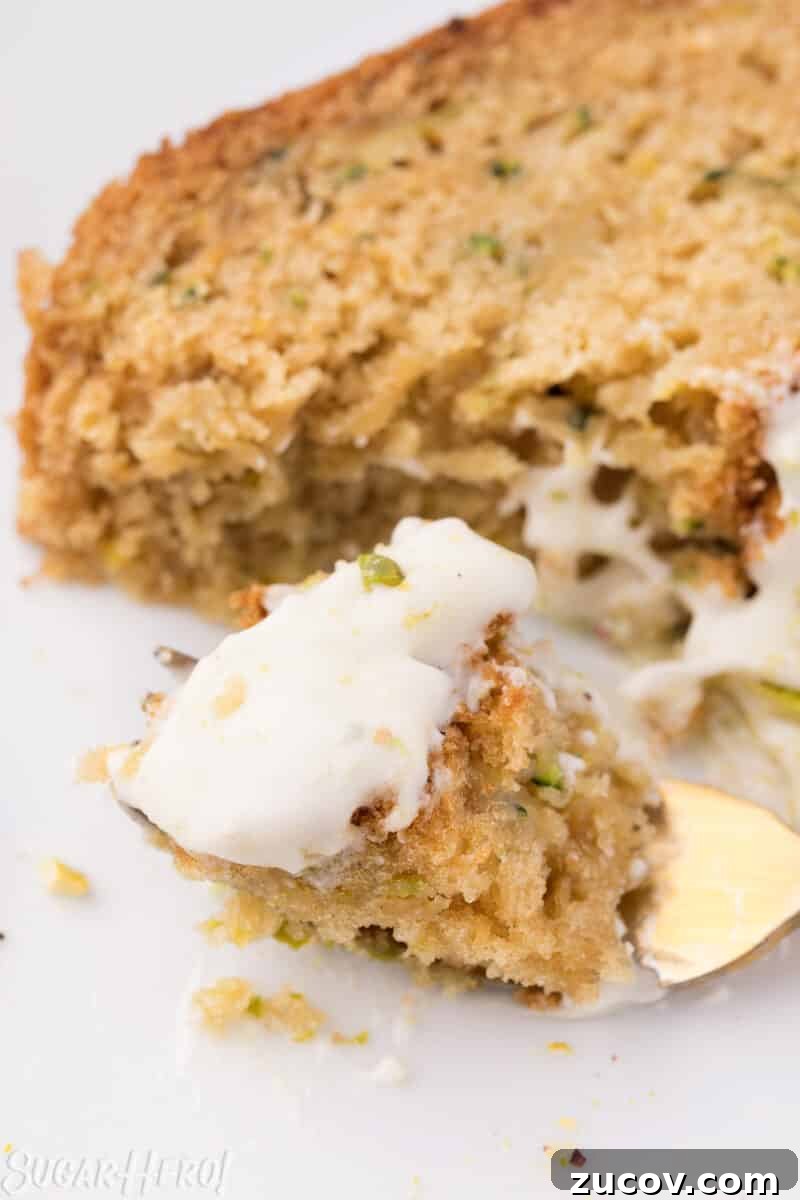 Moist Zucchini Bread Recipe with Cinnamon and Walnuts 10 Close-up of a bite of zucchini bread, frosted with cream cheese frosting, on a gold fork.