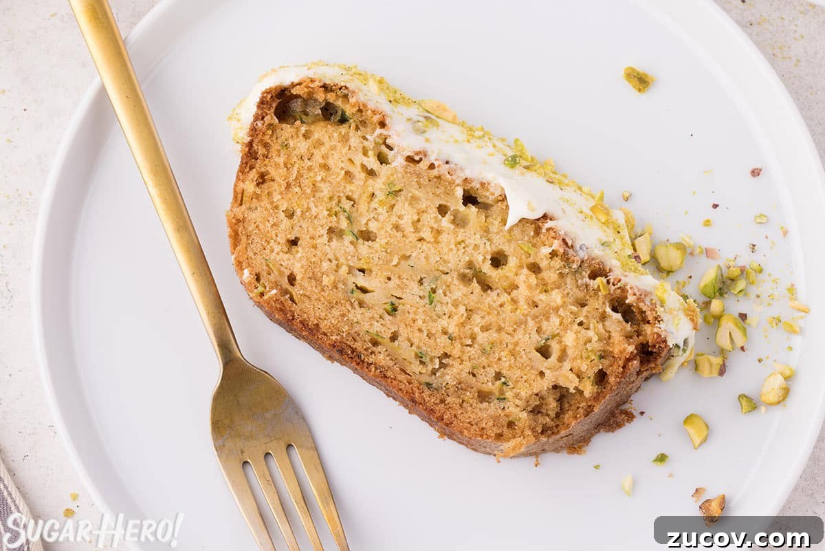 Moist Zucchini Bread Recipe with Cinnamon and Walnuts 5 Slice of zucchini bread on a white plate with a gold fork next to it.