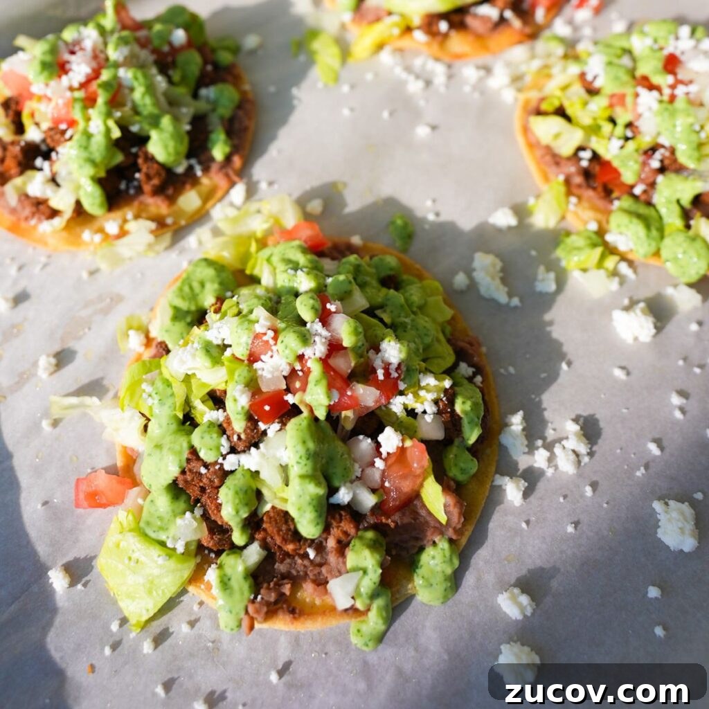 Crispy Ground Beef Tostadas with Fresh Salsa and Cheese 2 Ground beef tostadas topped with refried beans, lettuce, tomatoes, onions, queso fresco and cilantro lime sauce.
