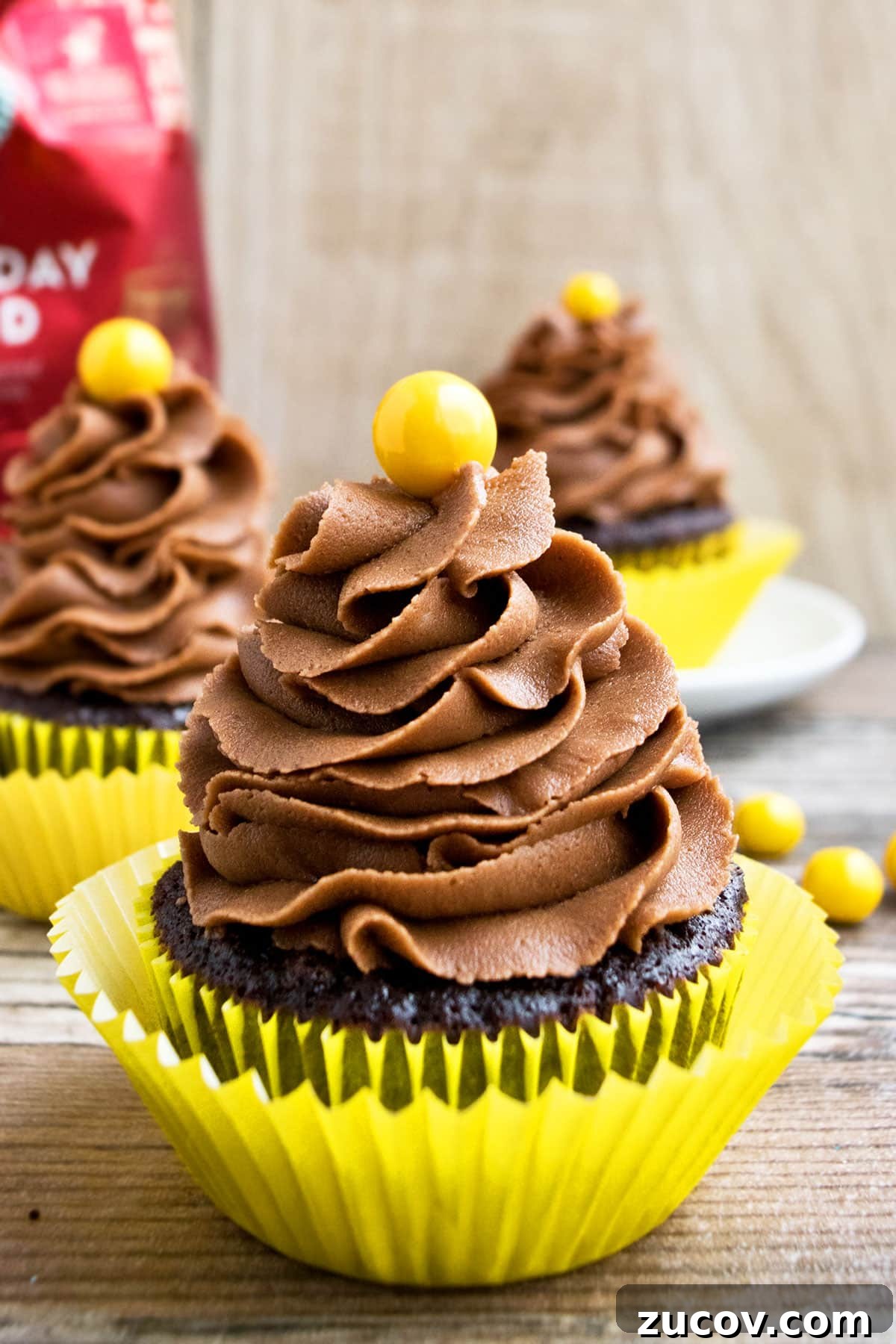 Mocha Coffee Cupcakes with Rich Espresso Frosting 3 Homemade Mocha Cupcakes in Yellow Liner on Rustic Background.