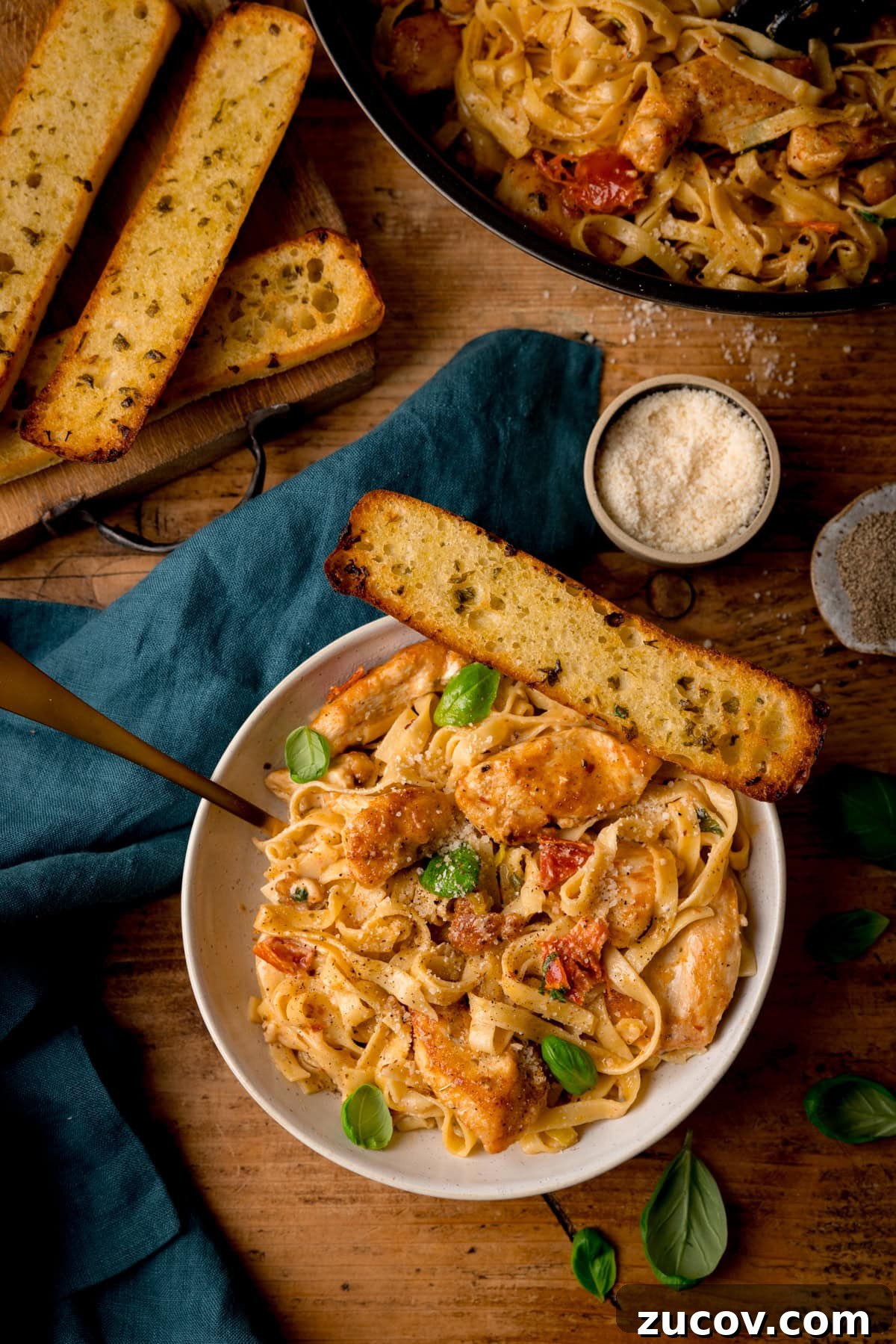 Creamy Marry Me Chicken Pasta Recipe for Weeknight Dinners 4 A tall, overhead shot of Marry Me Chicken Pasta in a white bowl with a gold fork and garlic bread.