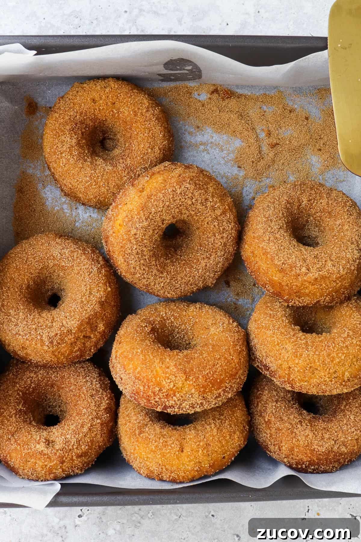 Gluten-Free Pumpkin Donuts Recipe That Actually Works 2 Donuts in the tray with a knife.
