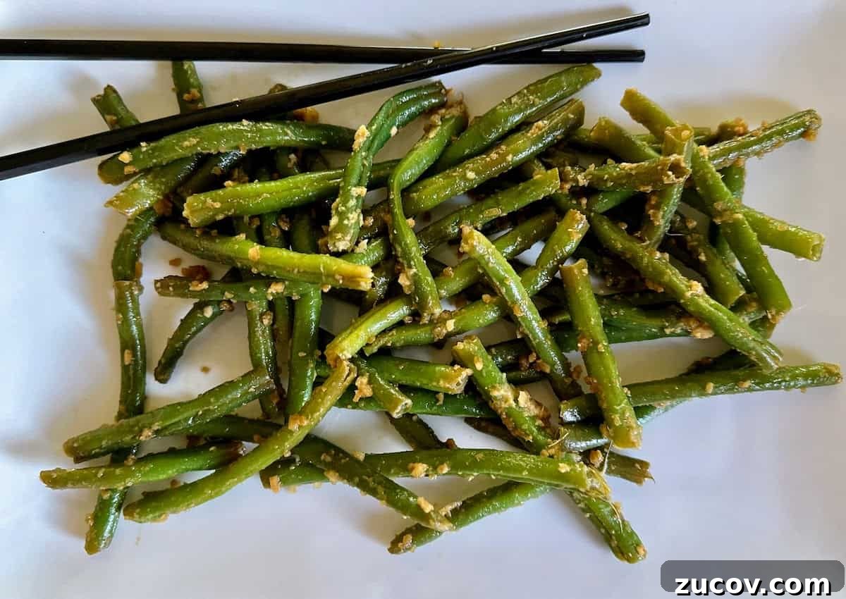 Crispy Asian-Style Garlic Green Beans Recipe 2 Asian style green beans recipe on a plate with chopsticks.