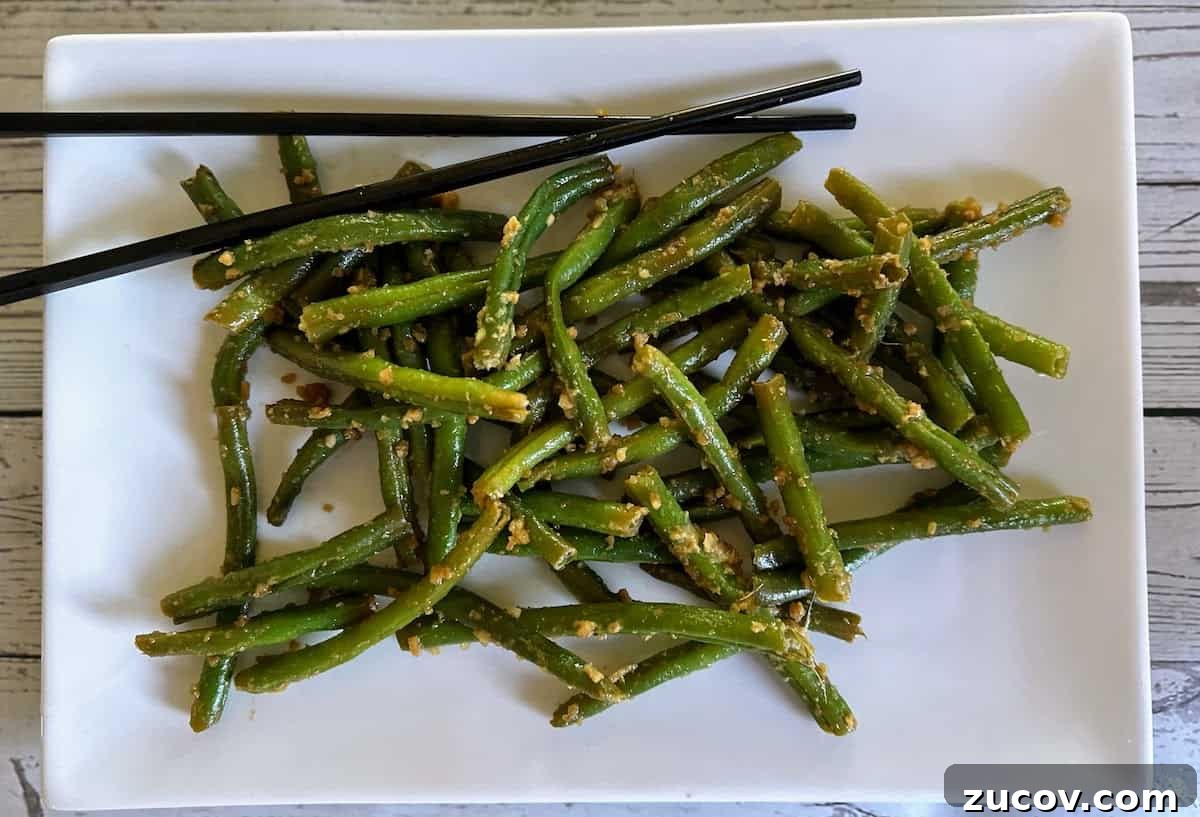 Crispy Asian-Style Garlic Green Beans Recipe 5 Asian-style green beans served on a platter with chopsticks.