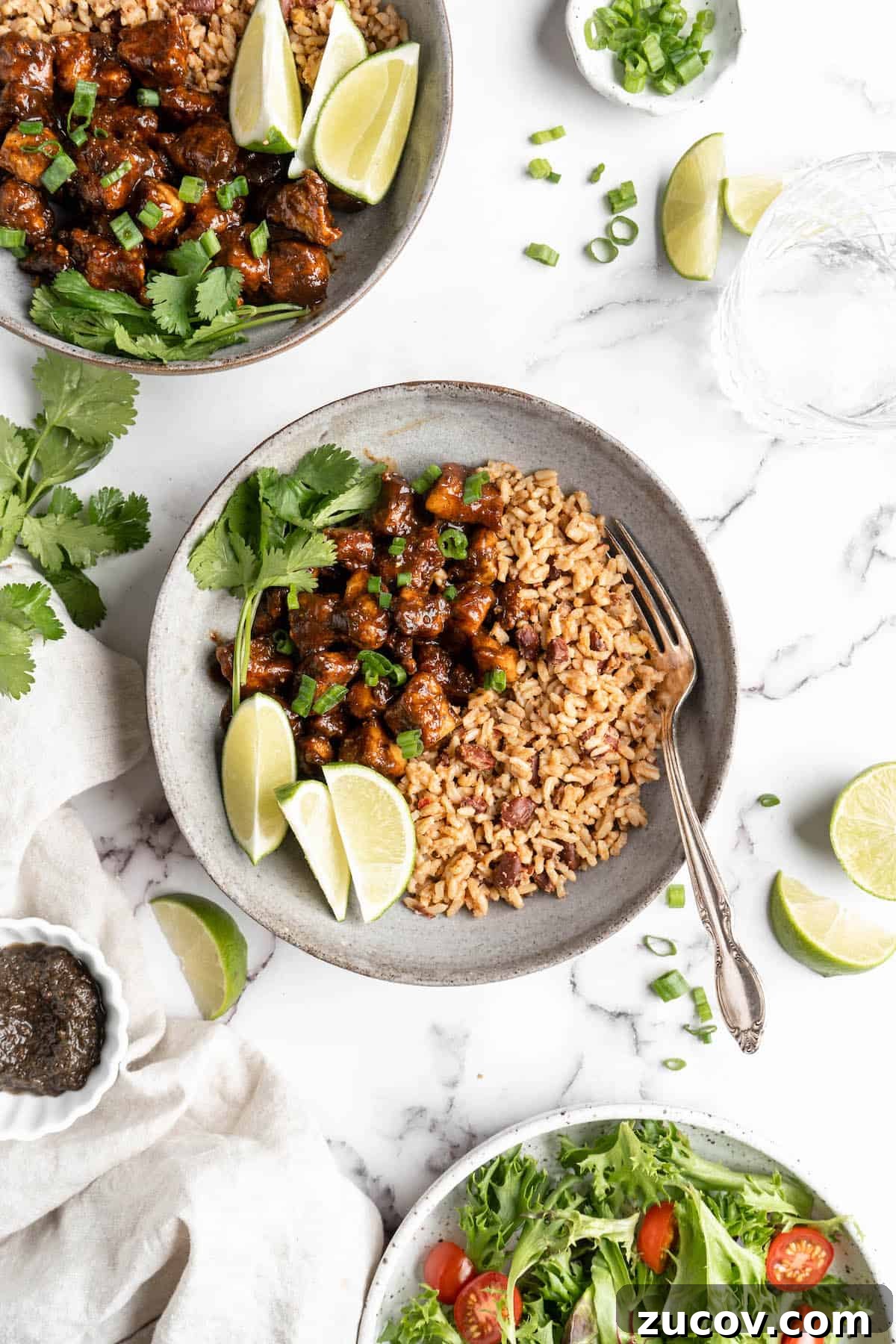 This Jamaican jerk tofu is the real deal! It's spicy, saucy, and just a little bit sweet. It's also super easy to make for a weeknight meal! Overhead view of jerk tofu in bowls with rice and lime wedges