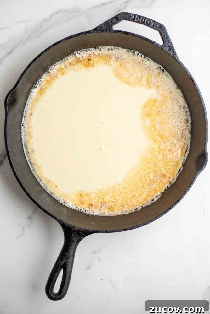 Blueberry Dutch Baby Pancake Recipe for Brunch and Dessert 6 Pancake batter poured into a cast iron skillet.
