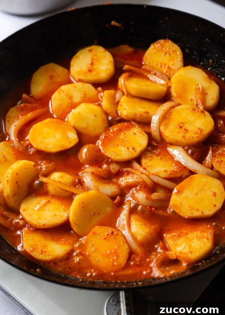 Spicy Korean Braised Potatoes (Maeun Gamja Jorim) 10 Potatoes simmering in spicy sauce in a skillet.