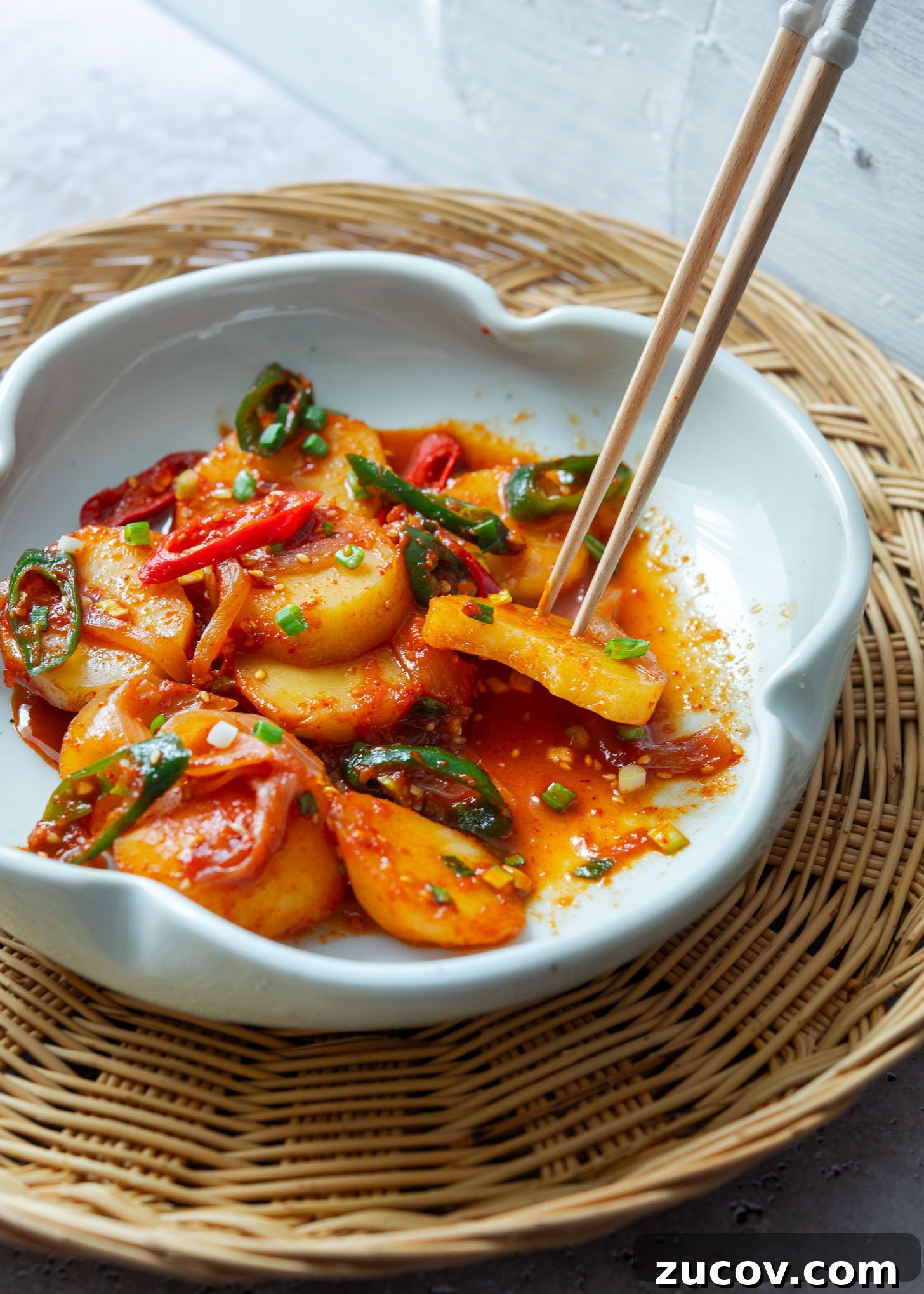 Spicy Korean Braised Potatoes (Maeun Gamja Jorim) 12 Chopsticks holding a piece of spicy potato.