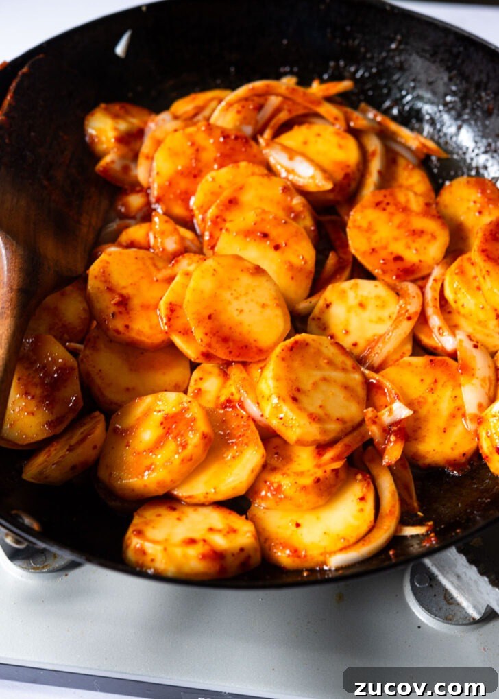 Spicy Korean Braised Potatoes (Maeun Gamja Jorim) 9 Spicy sauce added to the potato in a skillet.