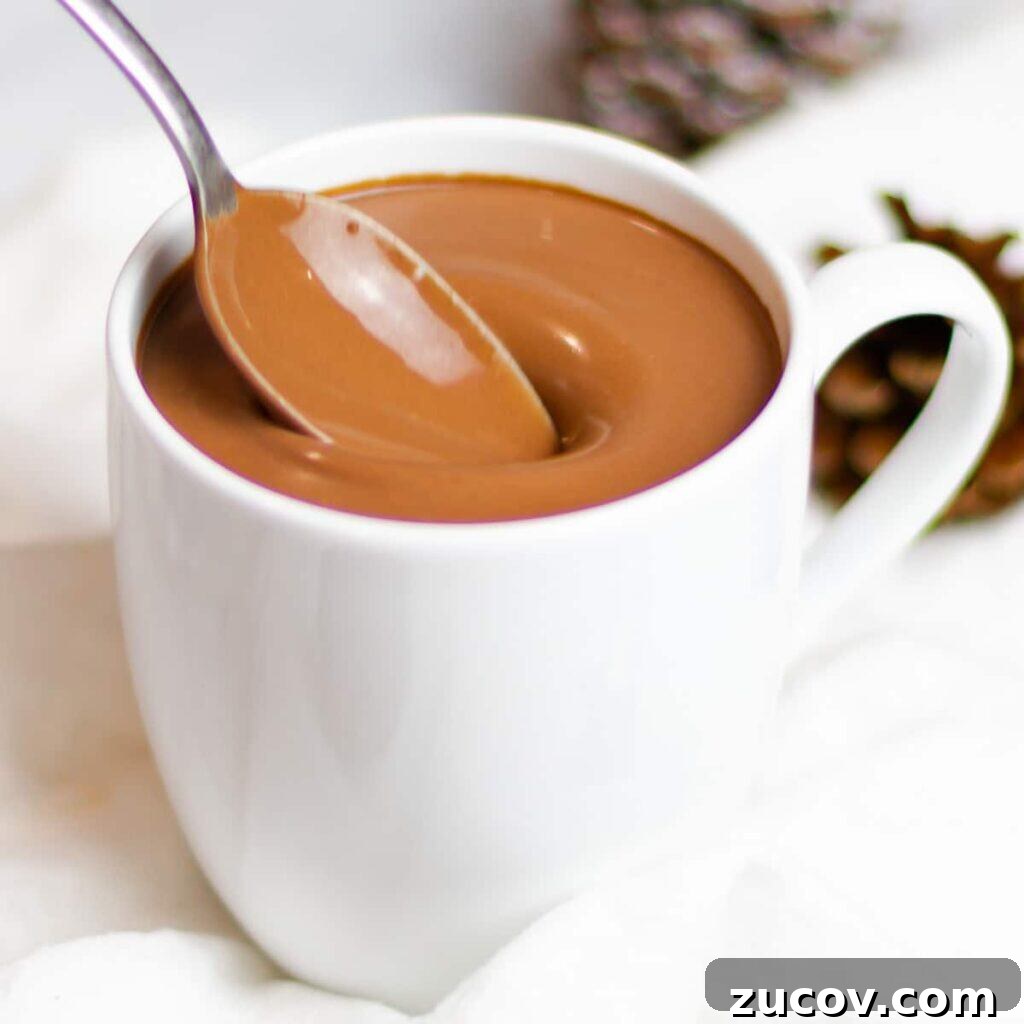 5-Minute Chocolate Ganache Recipe for Cakes, Glazes & Dips 11 rich and creamy homemade hot chocolate in a white mug with a spoon