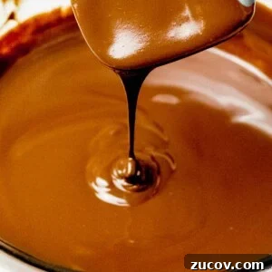 5-Minute Chocolate Ganache Recipe for Cakes, Glazes & Dips 15 chocolate ganache dripping off a spatula into a glass bowl