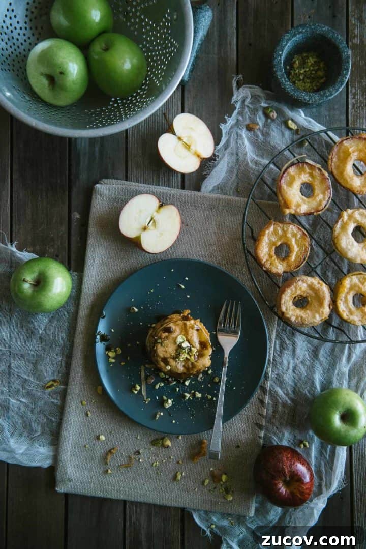 deep fried apple fritters served on a plate drizzled with pomegranate molasses and topped with crushed pistachios