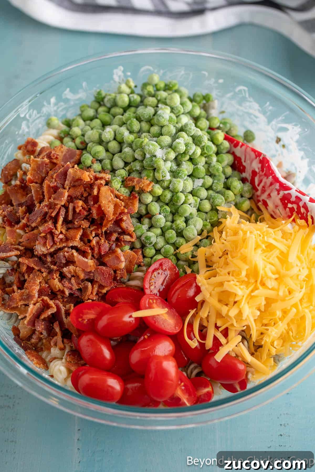 Creamy Bacon Ranch Pasta Salad with Crispy Bacon Crumbles 5 A large bowl filled with pasta, cherry tomatoes, bacon, peas, and cheese.