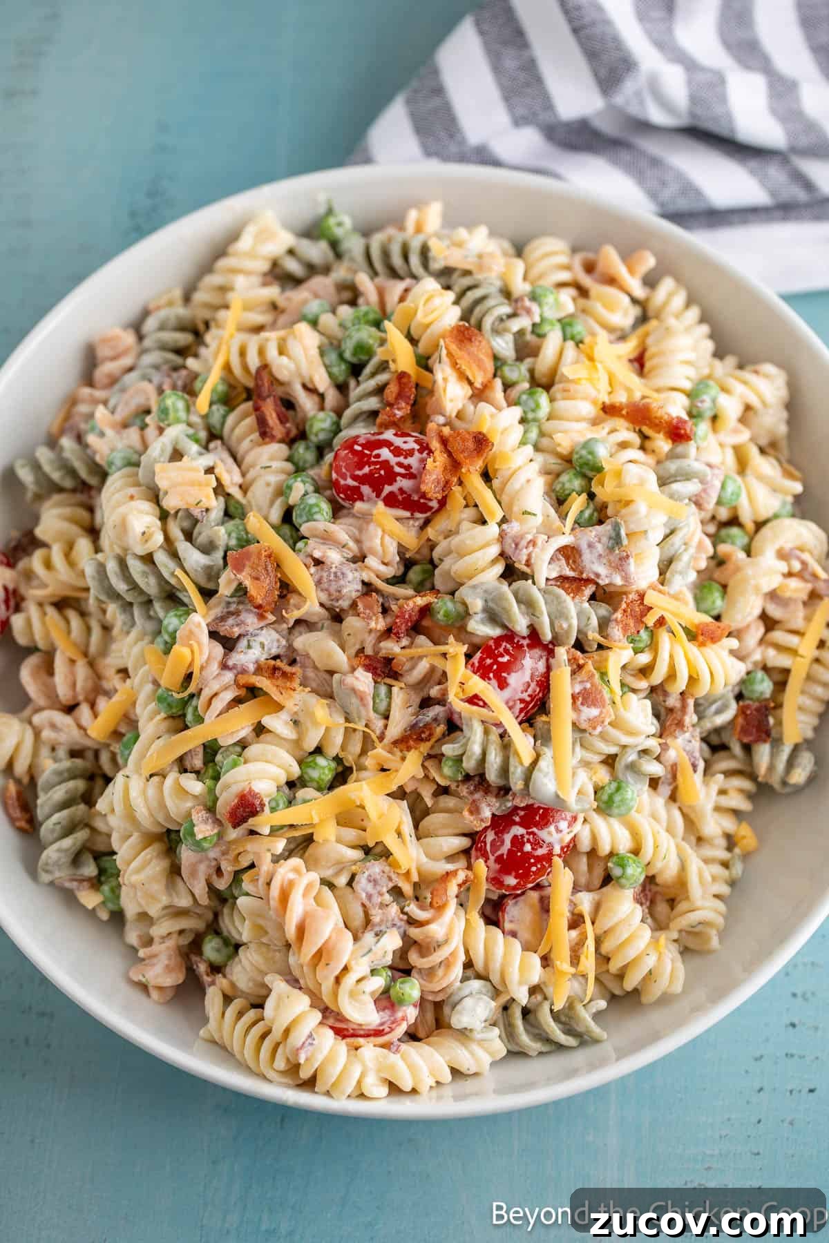 Creamy Bacon Ranch Pasta Salad with Crispy Bacon Crumbles 6 Pasta salad with tomatoes and bacon in a large white bowl.