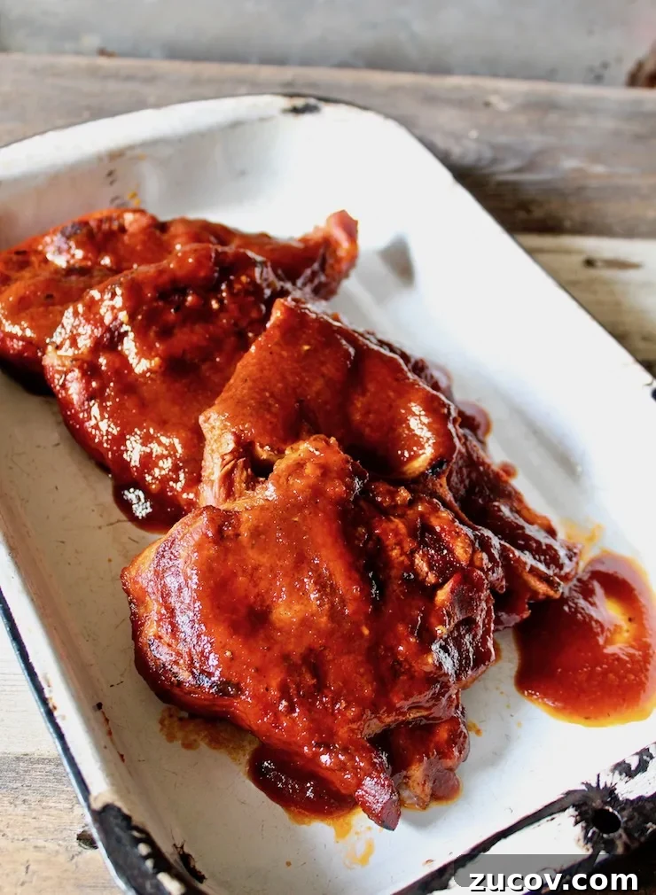 St. Louis Style BBQ Pork Steaks: Tender Grilled Recipe 3 St. Louis BBQ Pork Steaks in a pan with sauce for serving.