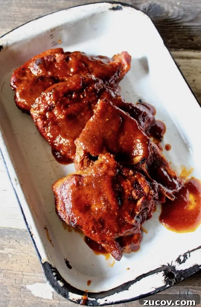 St. Louis Style BBQ Pork Steaks: Tender Grilled Recipe 5 St. Louis BBQ Pork Steaks overhead shot in pan with sauce.