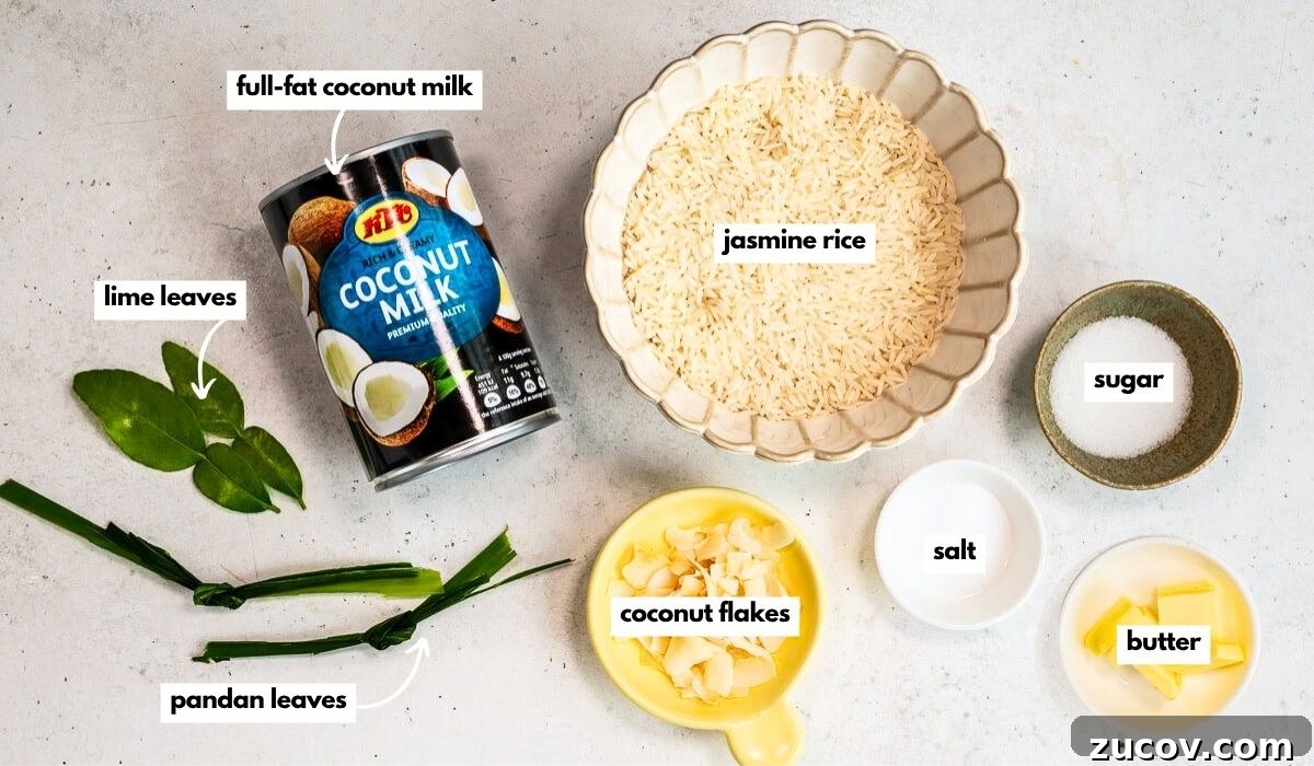 Coconut Rice Recipe: Creamy, Fragrant Side Dish in 30 Minutes 4 A can of coconut milk, a bowl of jasmine rice, small bowls of sugar, salt, and butter, a dish of coconut flakes, two pandan leaves, and two lime leaves are arranged on a light surface. Each item is labeled.