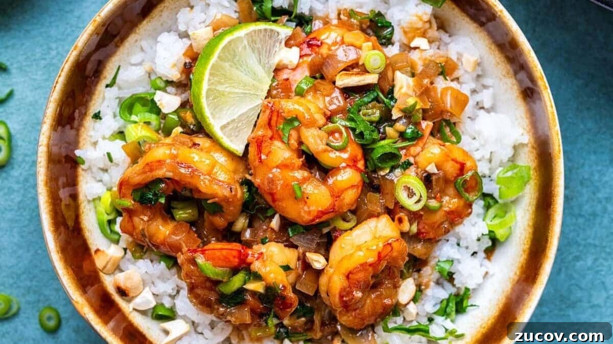 Coconut Rice Recipe: Creamy, Fragrant Side Dish in 30 Minutes 7 A bowl of coconut jasmine rice topped with saucy coconut shrimp, chopped green onions, cilantro, and a lime wedge. Nearby are bowls of chopped nuts, sliced green onions, and more shrimp in sauce.
