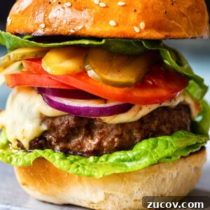 Juicy Homemade Burger Recipe for Perfect Grilling 7 homemade burger with cheese, tomatoes, onions and pickles on grey plate closeup