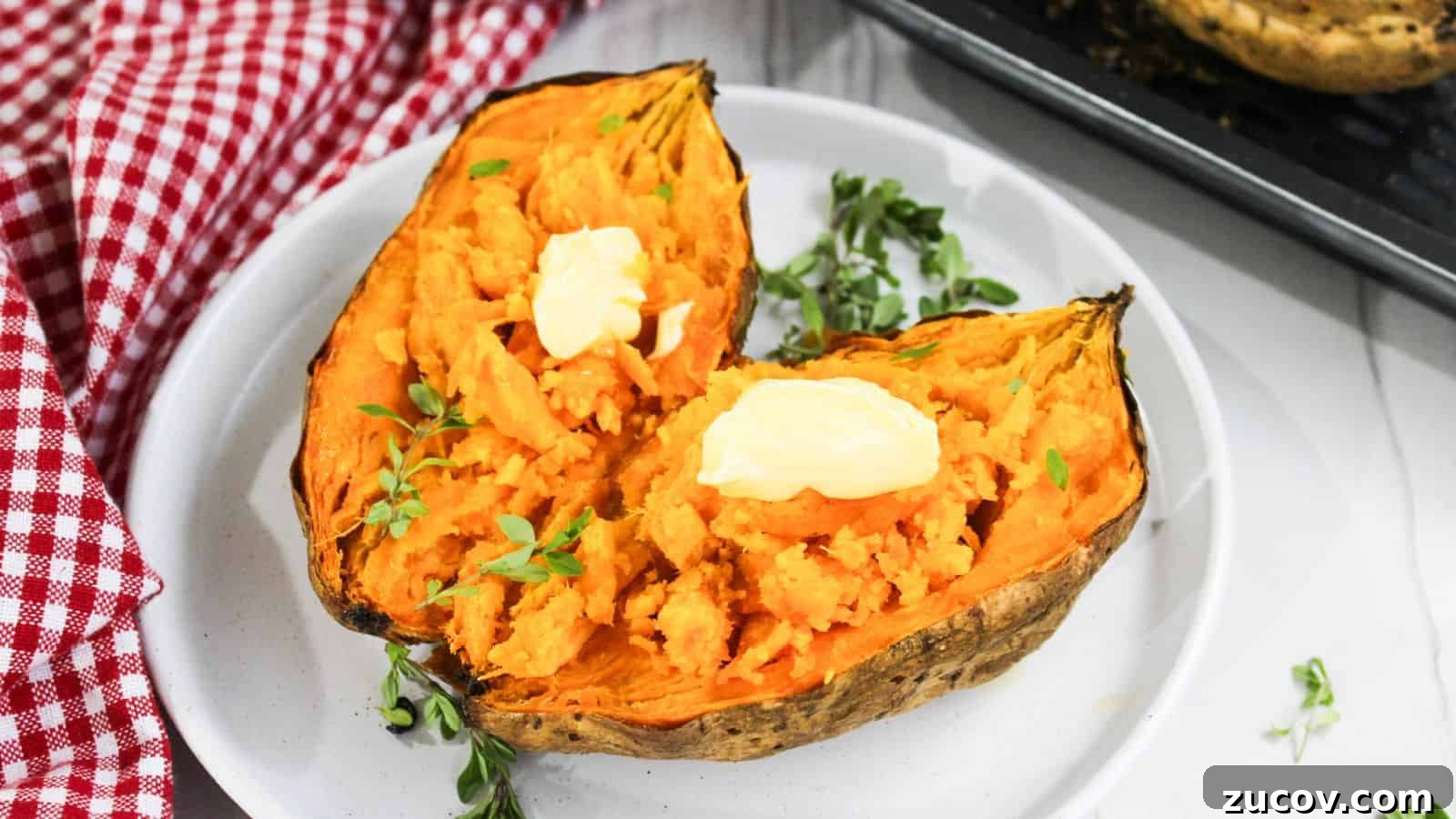 17 Comforting Side Dishes That Steal the Show 9 Two halves of baked sweet potato topped with butter and garnished with herbs on a white plate, with a red checkered napkin on the side.