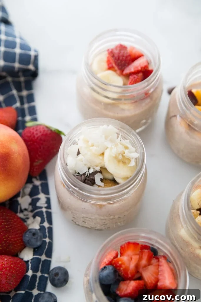 Creamy Overnight Oats: 5 Simple Recipes for Busy Mornings 3 Five meal prep Overnight Oats with various toppings on a marble backdrop. A blue kitchen towel sits nearby and with berries and peaches on top