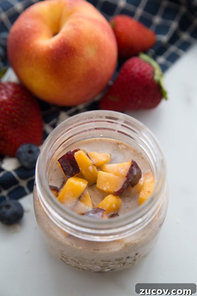 Creamy Overnight Oats: 5 Simple Recipes for Busy Mornings 9 A jar of peaches and cream overnight oats sitting next to a large peach and some strawberries