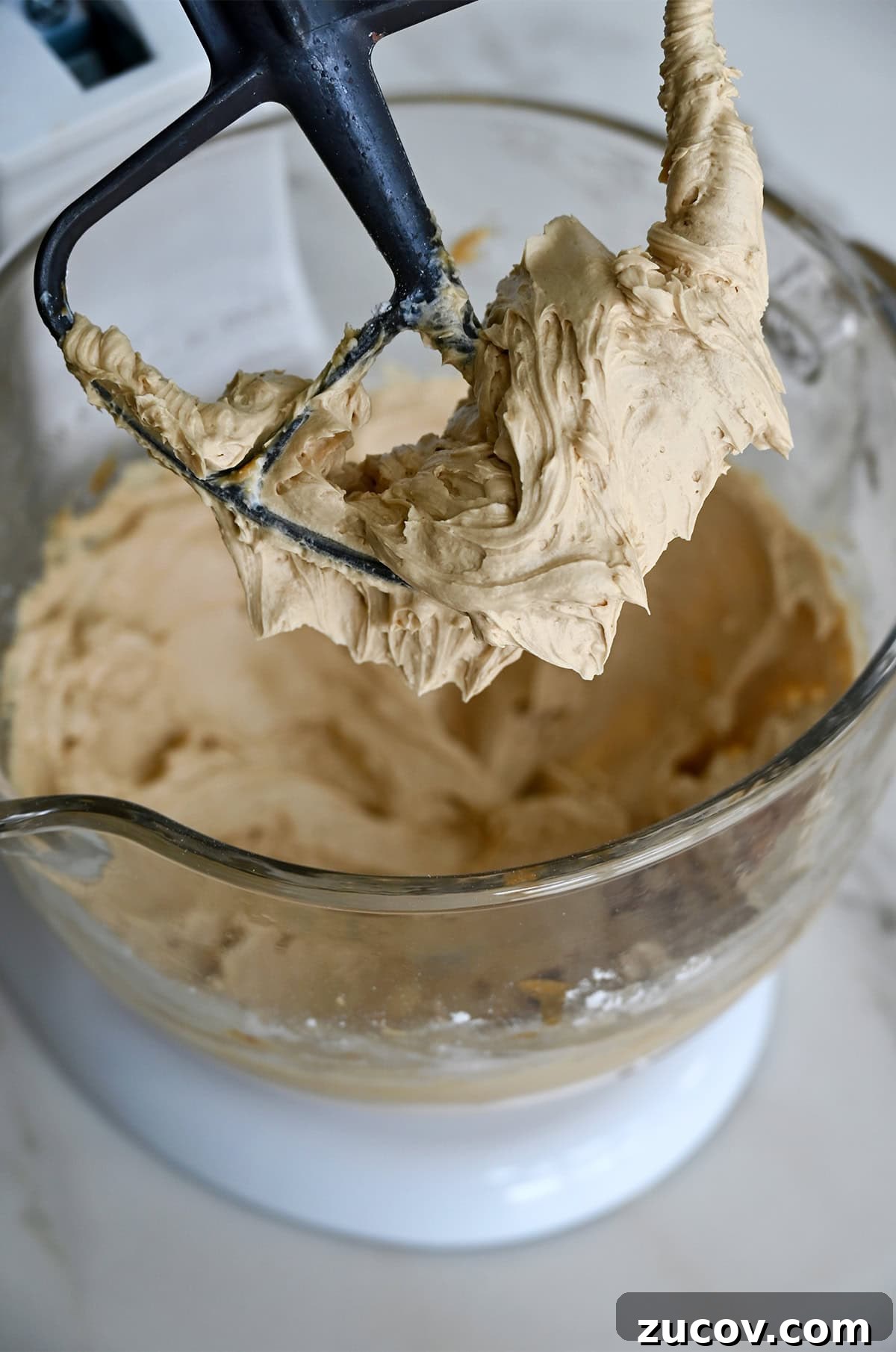 5-Minute Coffee Buttercream Frosting Recipe 3 Silky smooth coffee buttercream frosting covering the paddle attachment of a stand mixer.